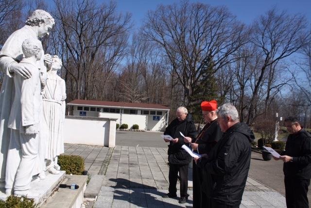 Cardinal Dolan prays with Salesian priests at a statue of St. John Bosco at the Shrine of Mary Help of Christians in Stony Point March 21. Flanking the cardinal were Father Stephen Ryan, S.D.B., left, and Father James McKenna, S.D.B.; standing in the back was Father Michael Pace, S.D.B.